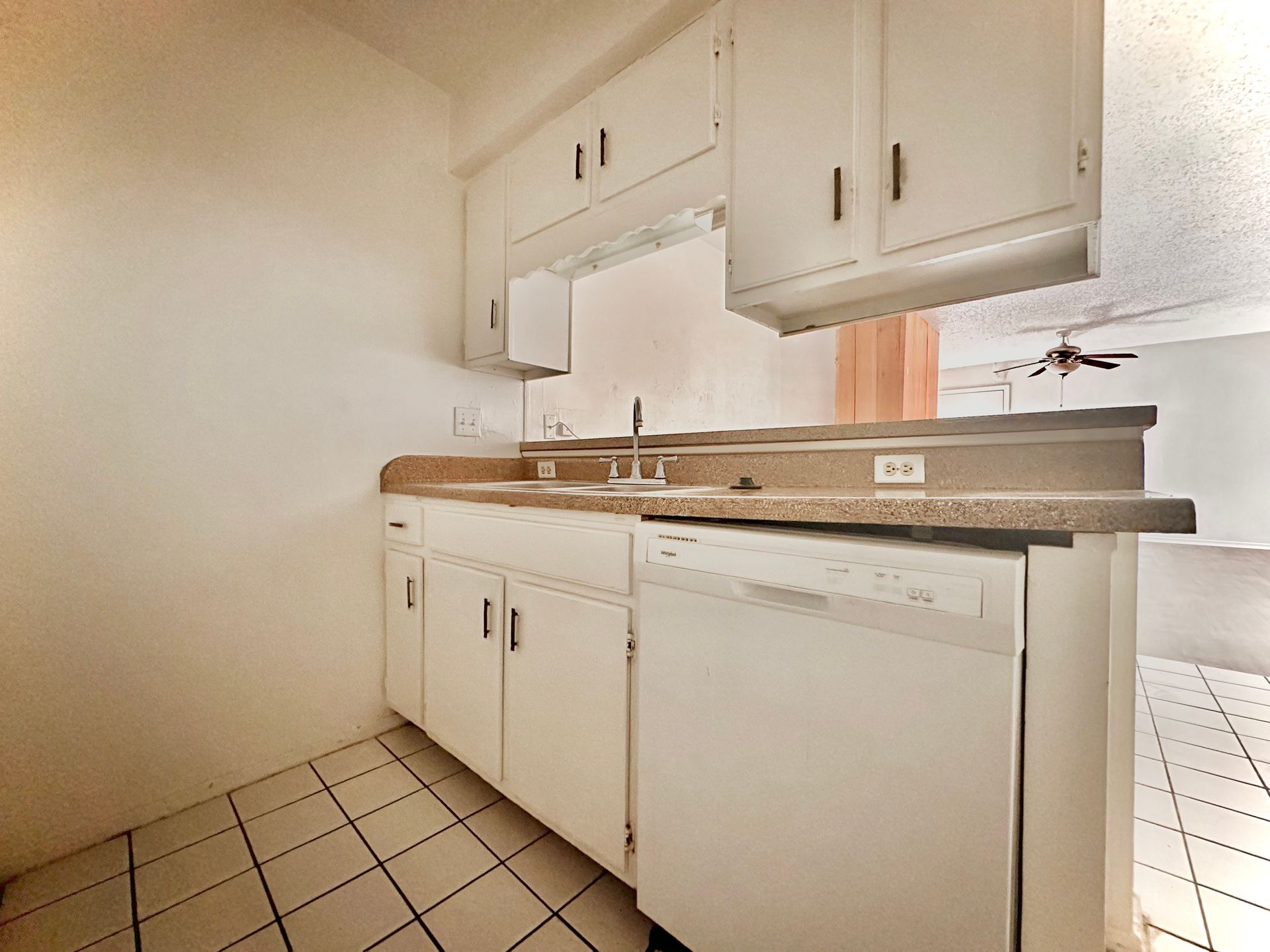 A kitchen with white cabinets and a white dishwasher