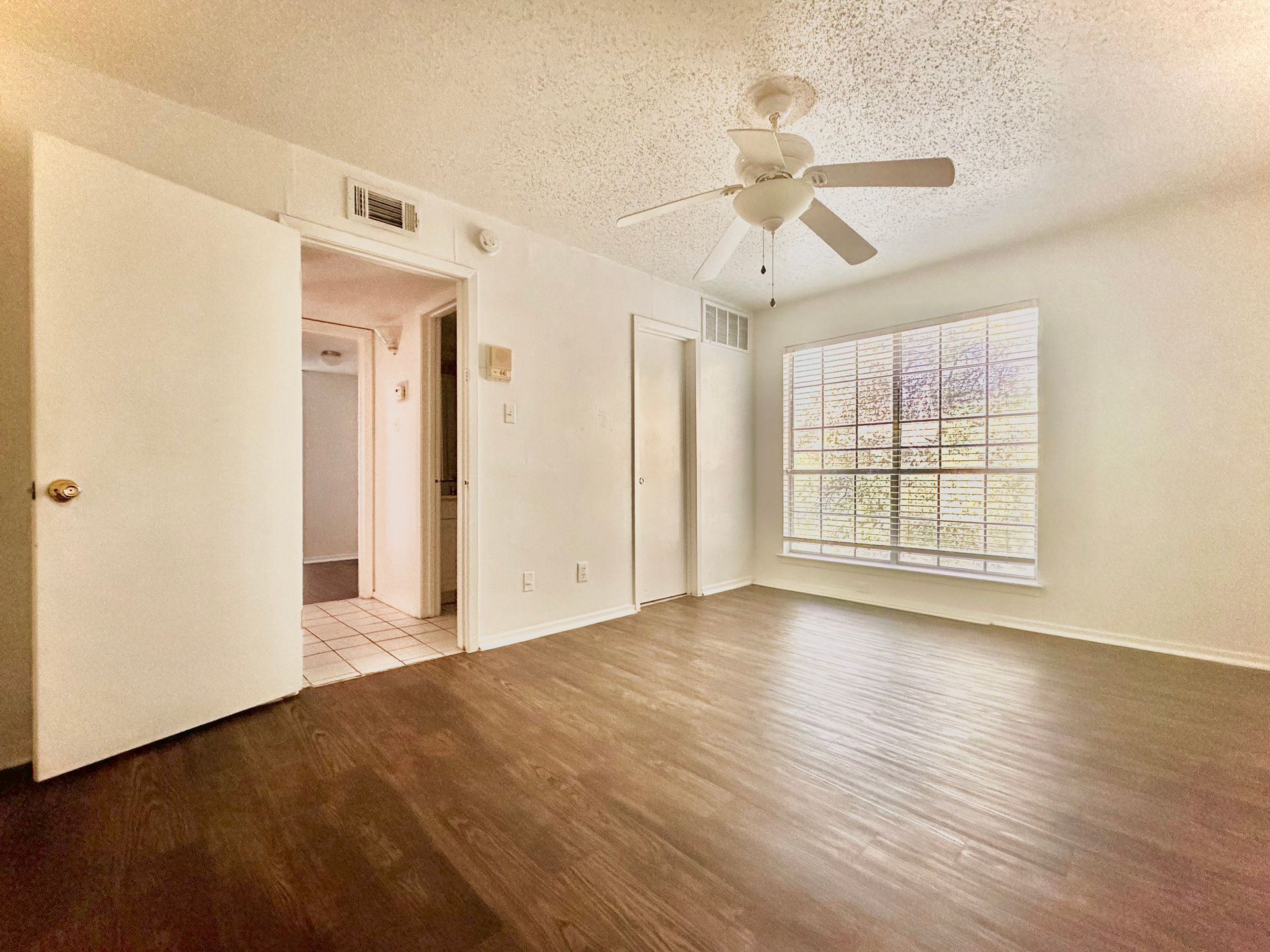 An empty living room with hardwood floors and a ceiling fan.