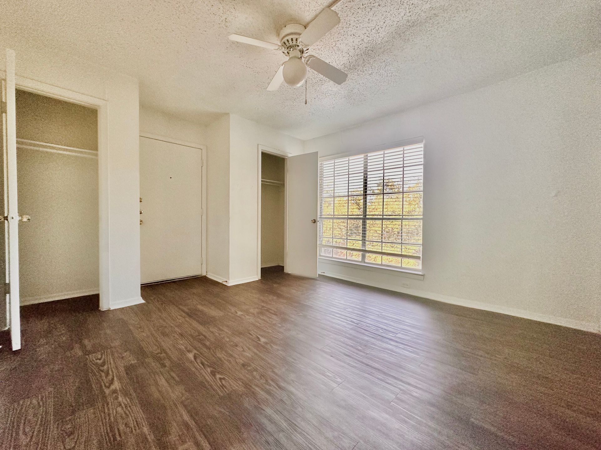 An empty room with hardwood floors and a ceiling fan.