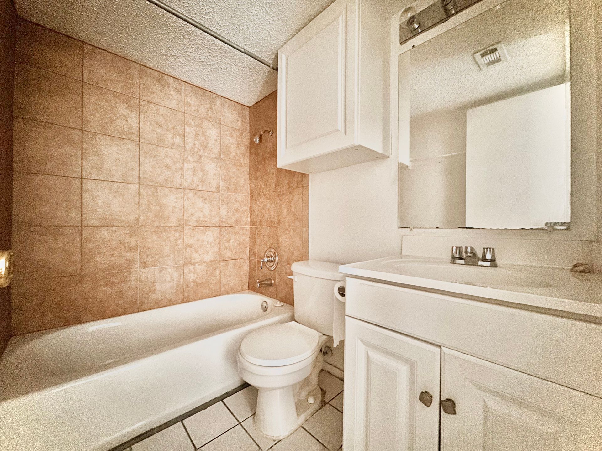 A bathroom with a toilet , sink , bathtub and mirror.