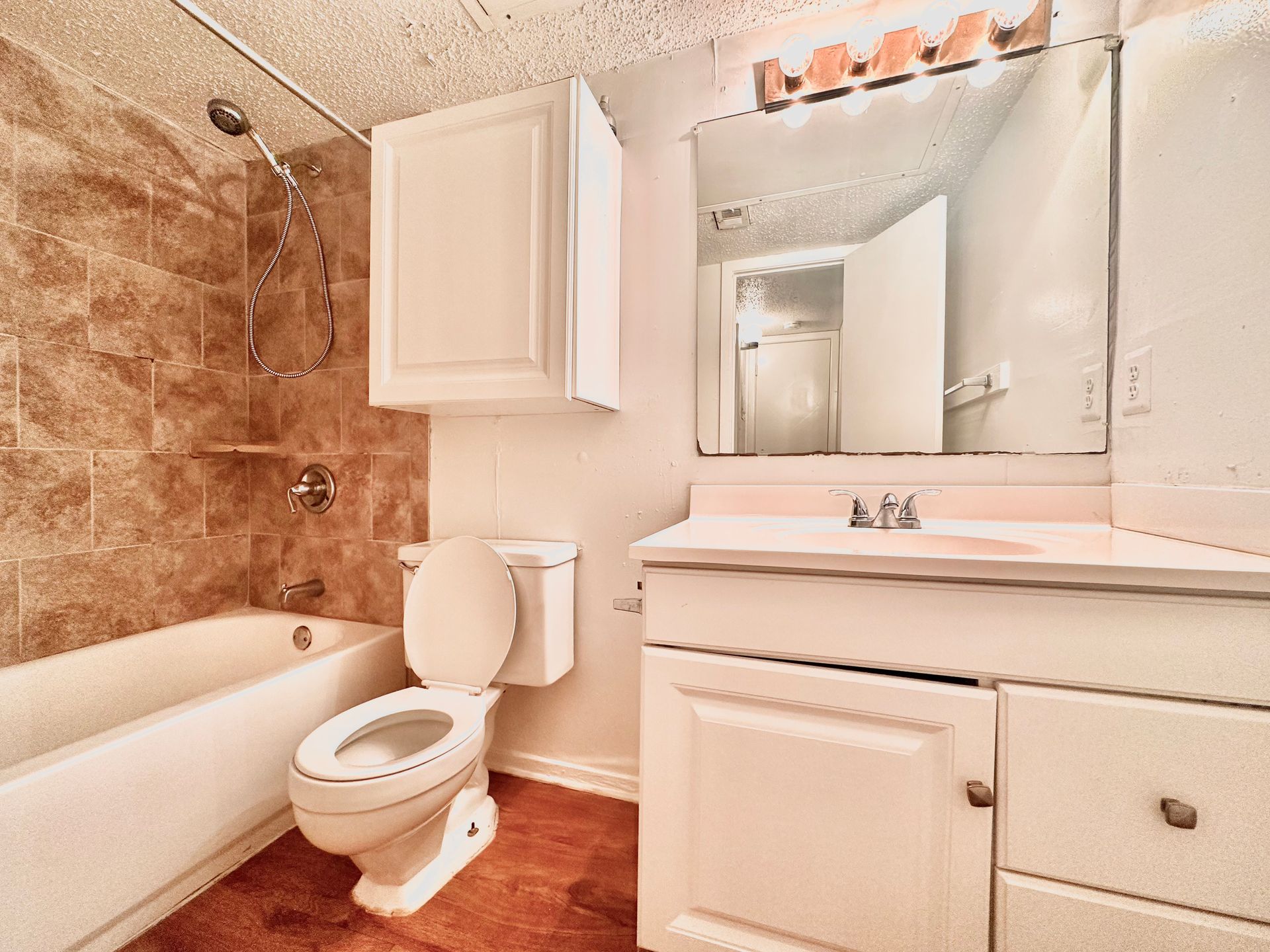 A bathroom with a toilet , sink , bathtub and mirror.