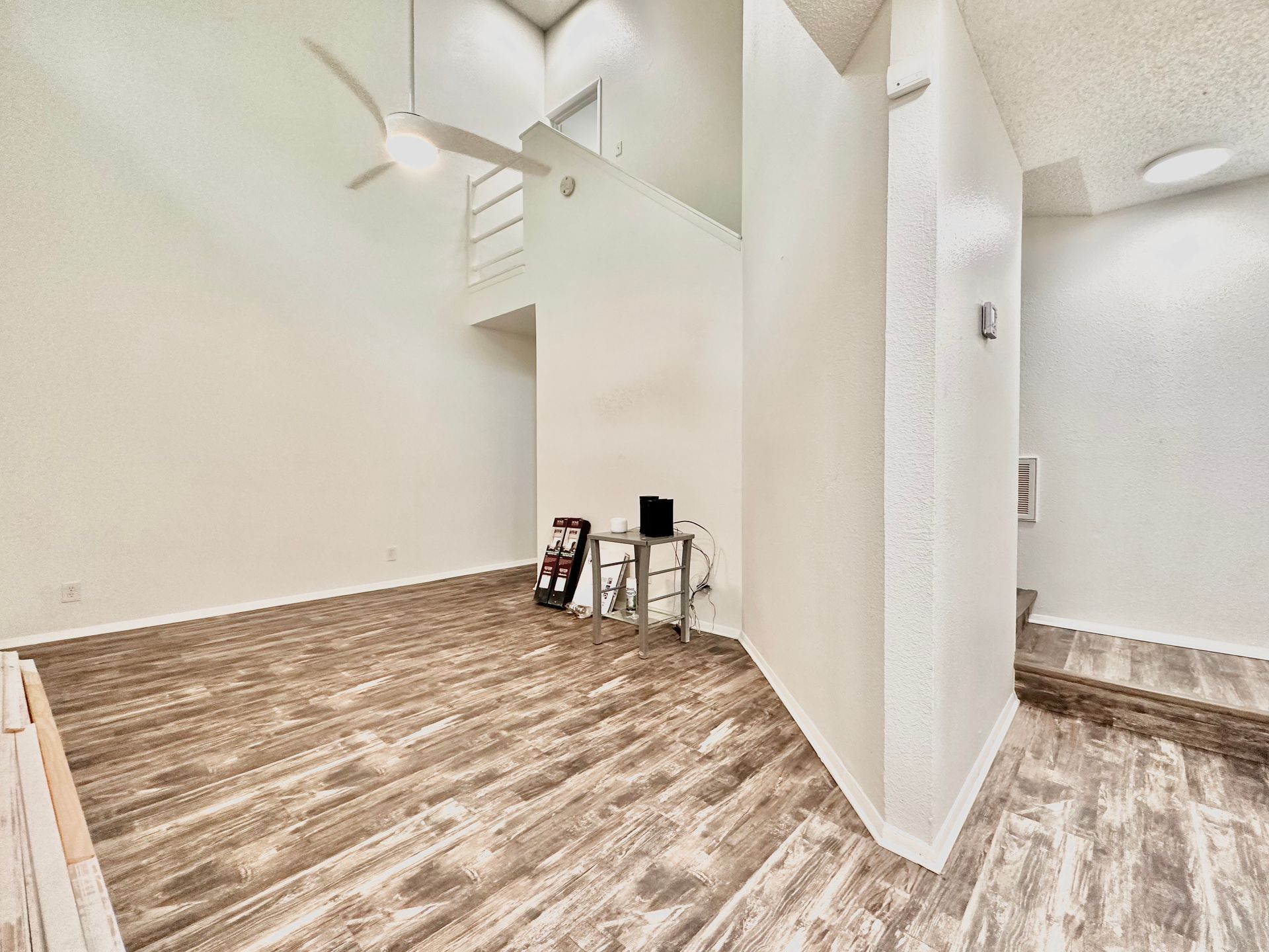 A living room with hardwood floors and a ceiling fan.