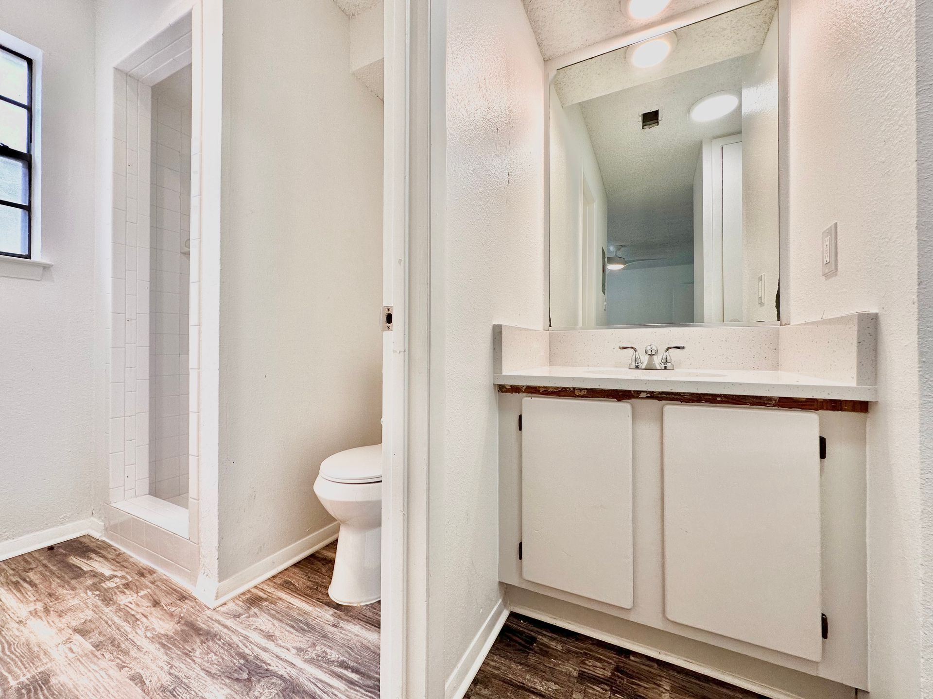A bathroom with a toilet , sink and mirror.