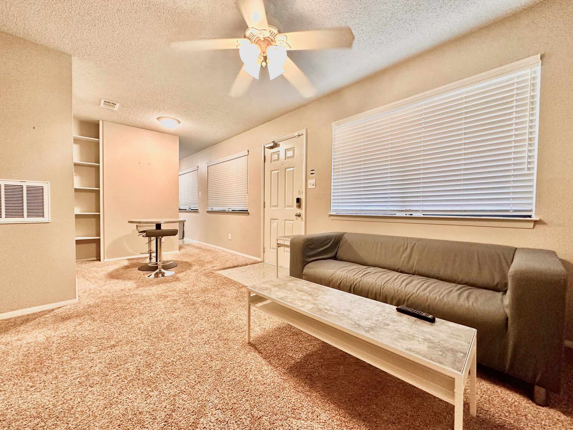 A living room with a couch , coffee table and ceiling fan