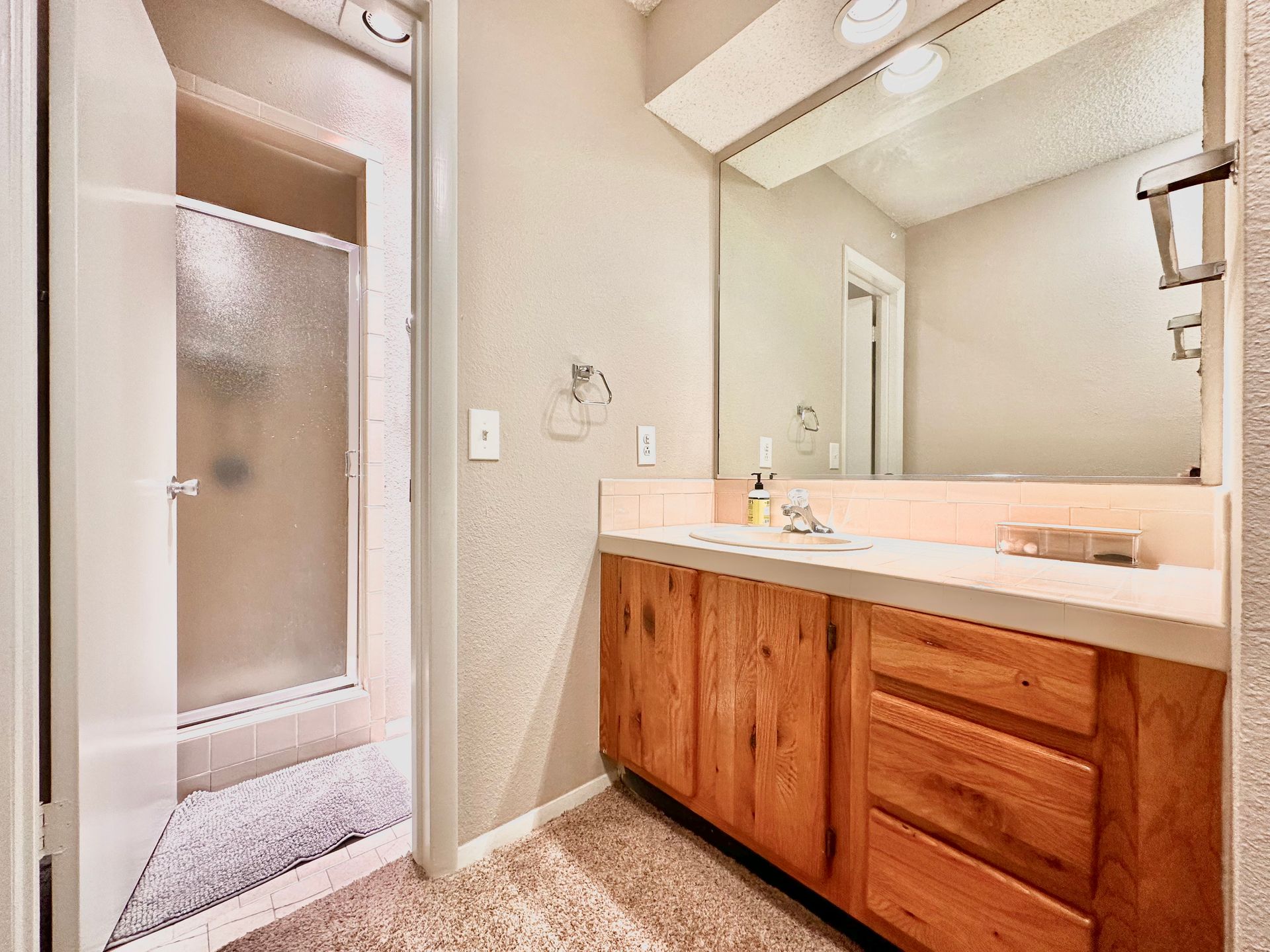 A bathroom with a sink , mirror and shower.