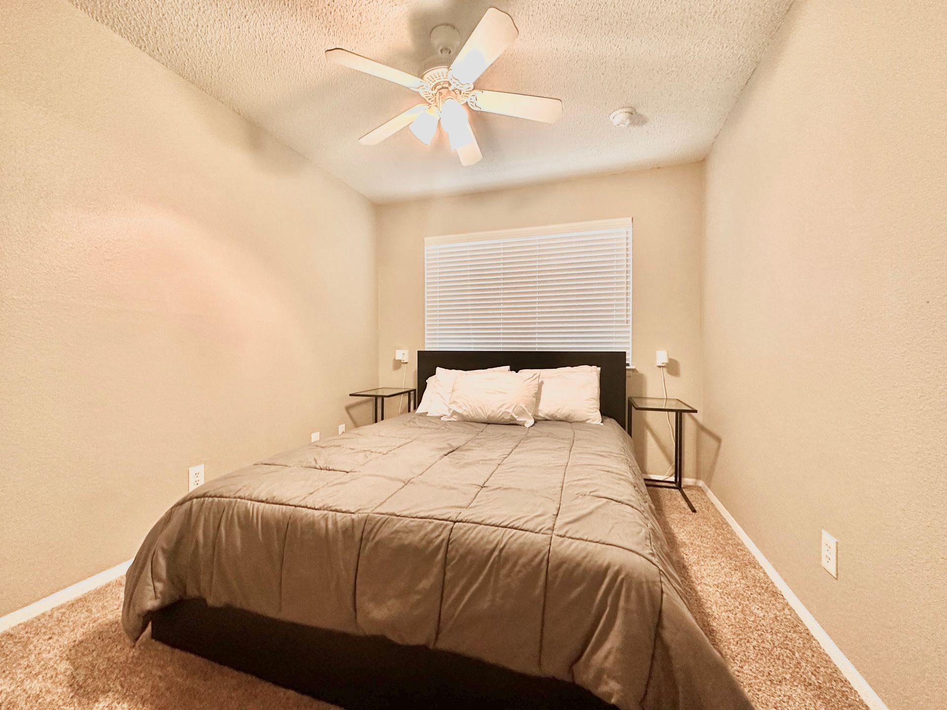 A bedroom with a bed and a ceiling fan