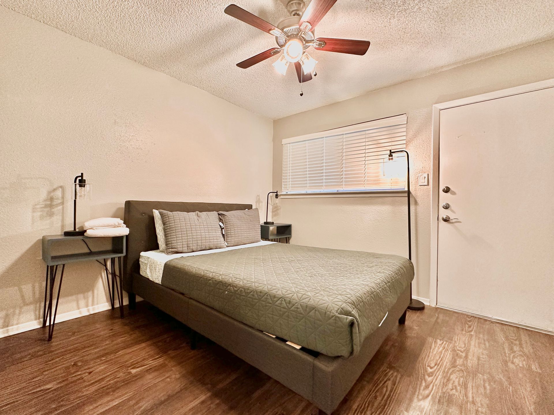 A bedroom with a bed , nightstand , and ceiling fan.