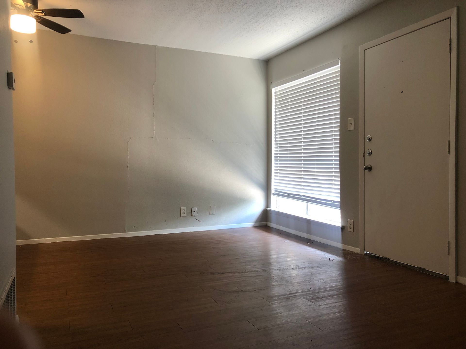 An empty living room with hardwood floors and a ceiling fan