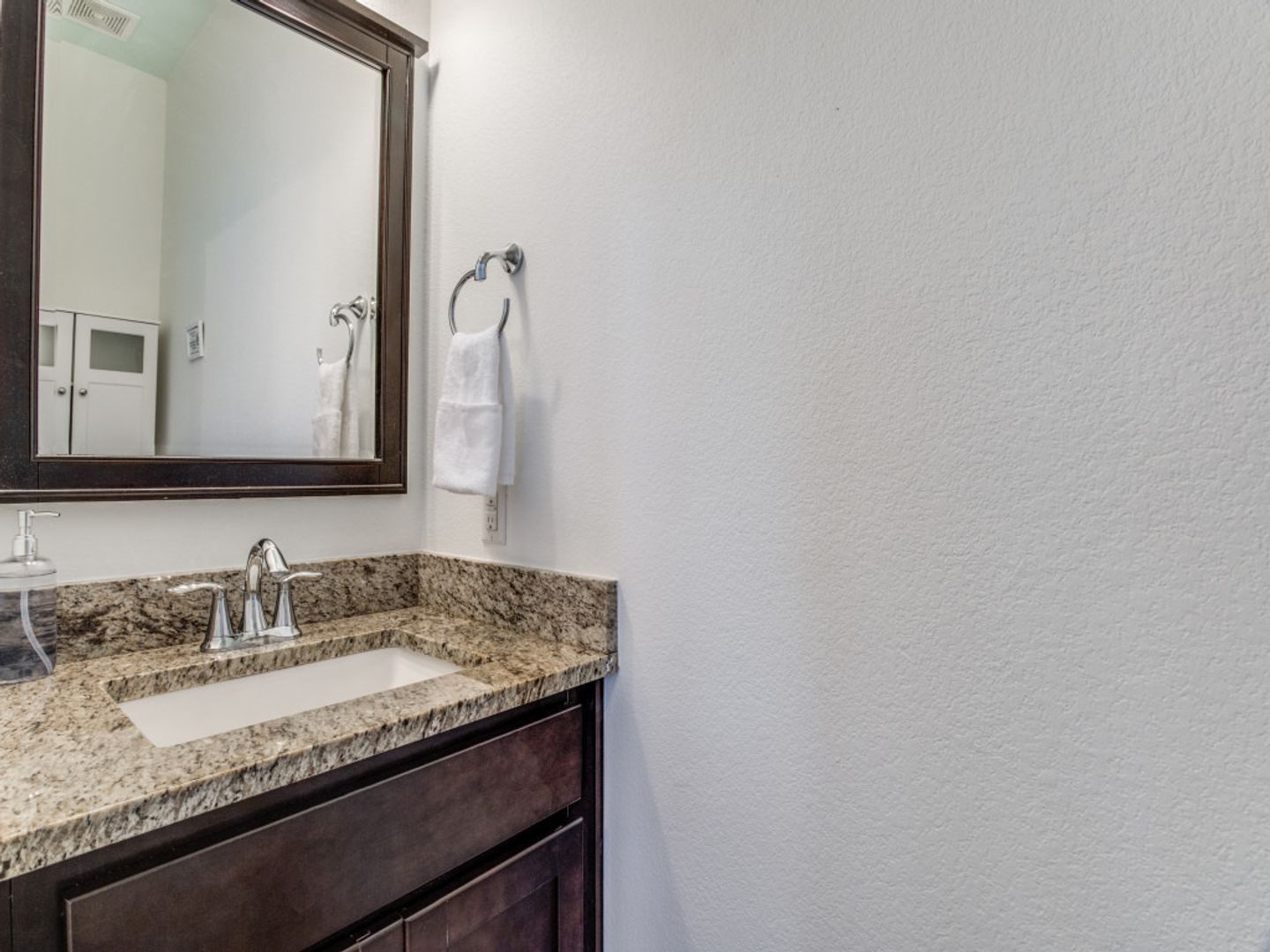 A bathroom with a sink , mirror and towel rack.