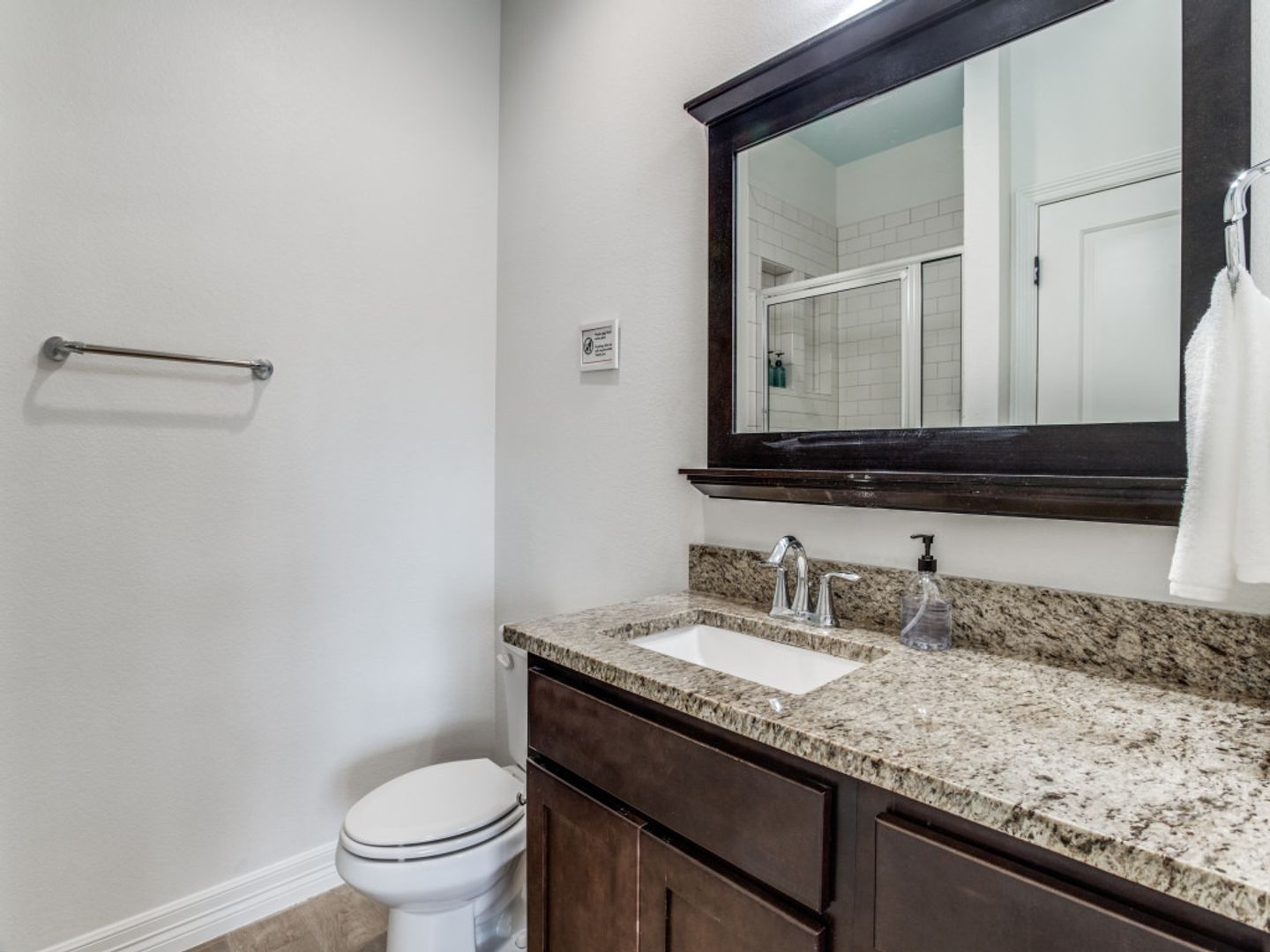 A bathroom with a toilet , sink and mirror.