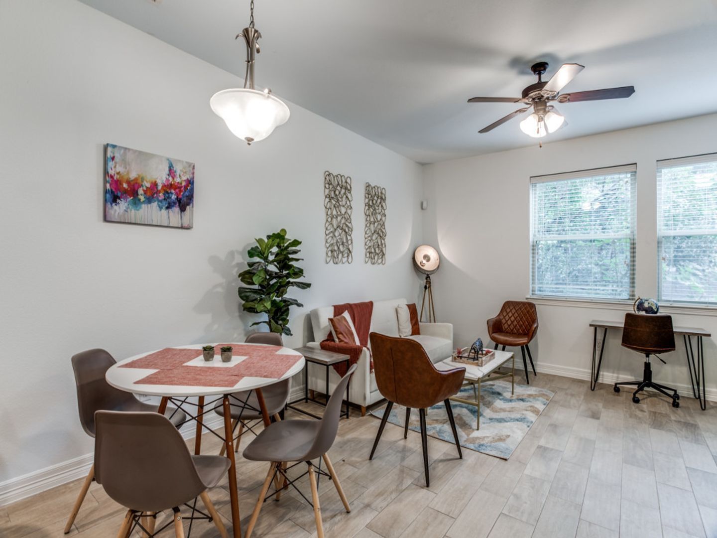 A living room with a table and chairs and a ceiling fan.