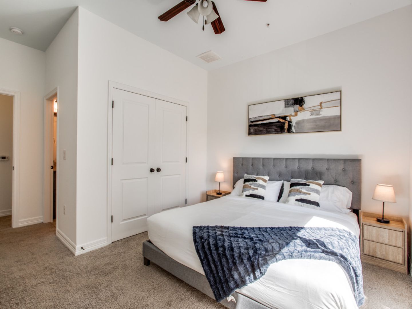A bedroom with a large bed and a ceiling fan