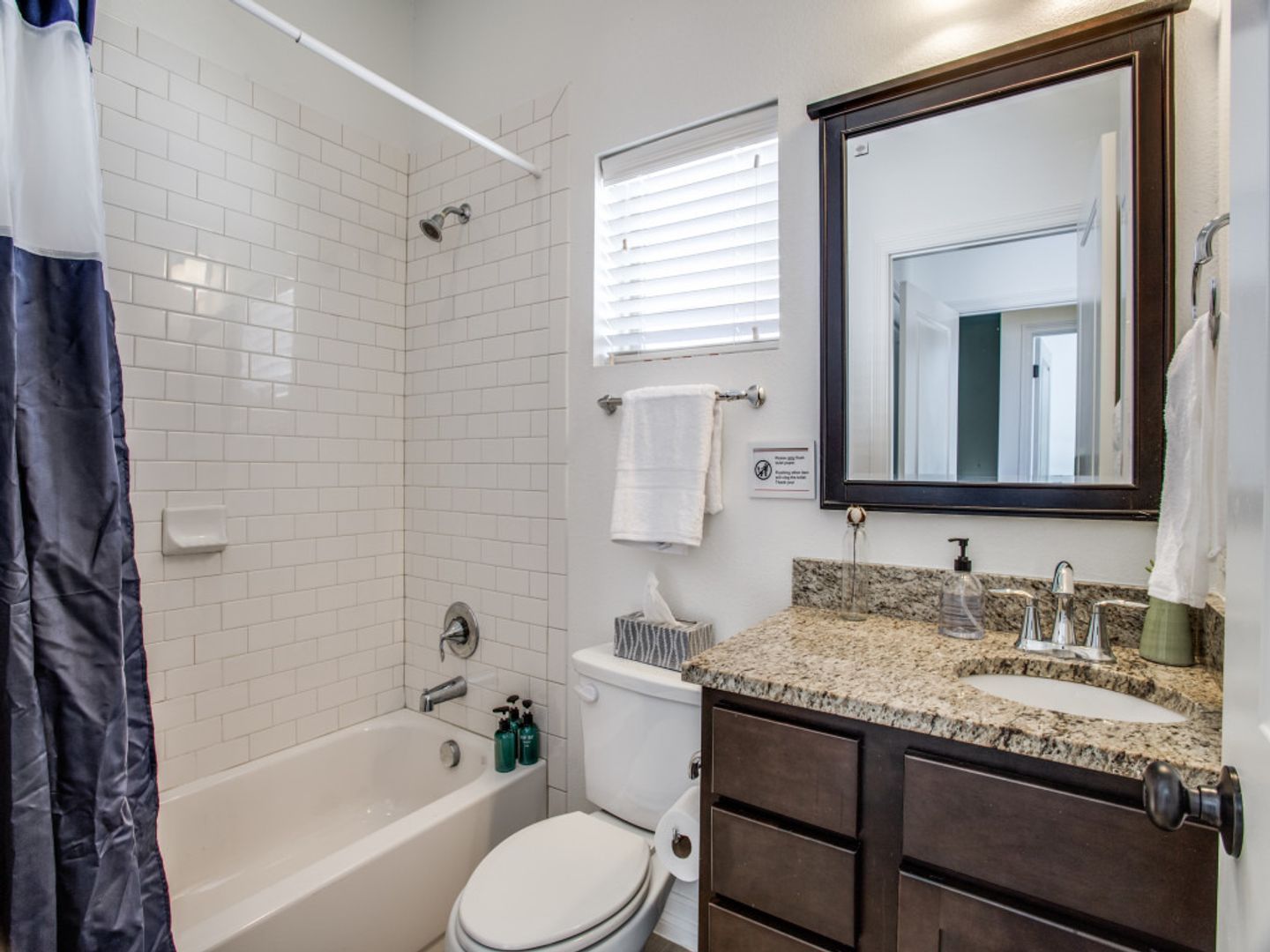 A bathroom with a toilet , sink , tub and mirror.