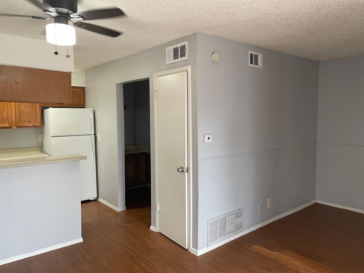 A living room with a ceiling fan and a refrigerator.