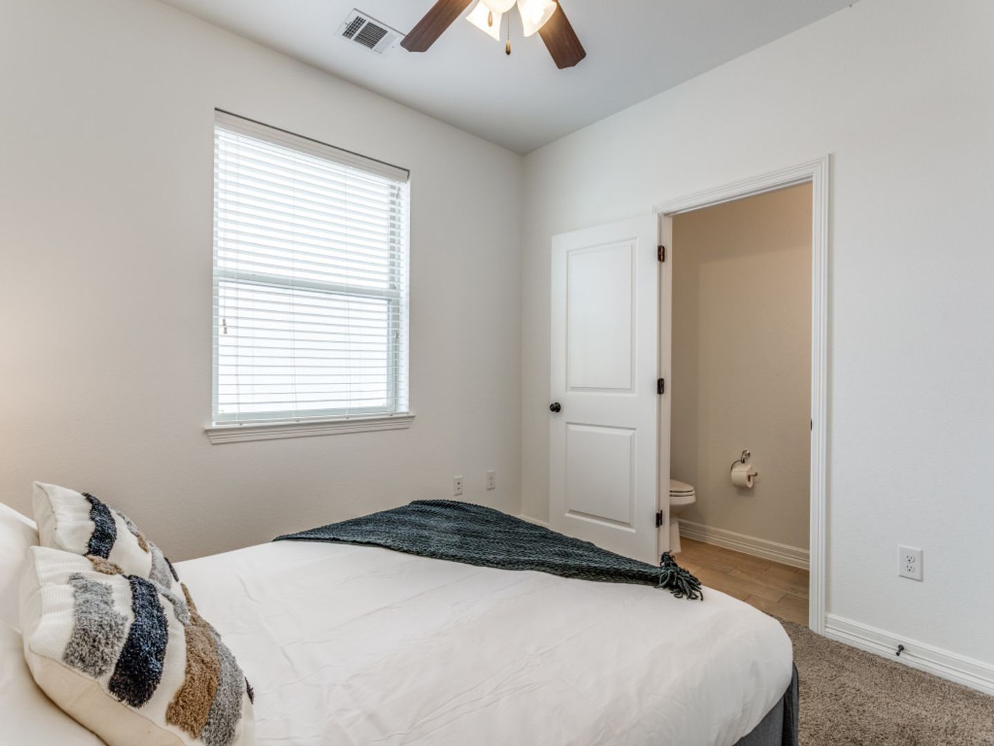 A bedroom with a bed , window and ceiling fan.