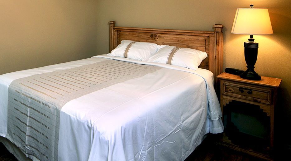 A bedroom with a bed , nightstand , lamp and television.