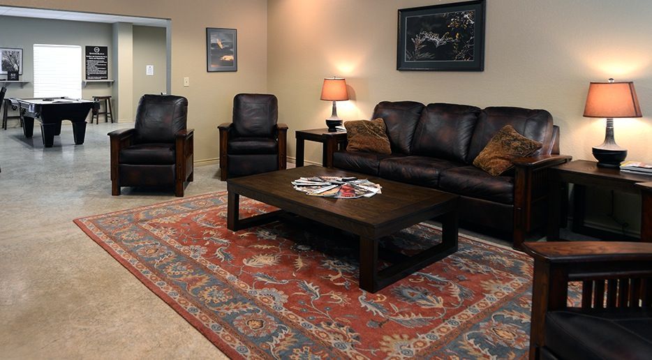 A living room with a couch and chairs and a pool table