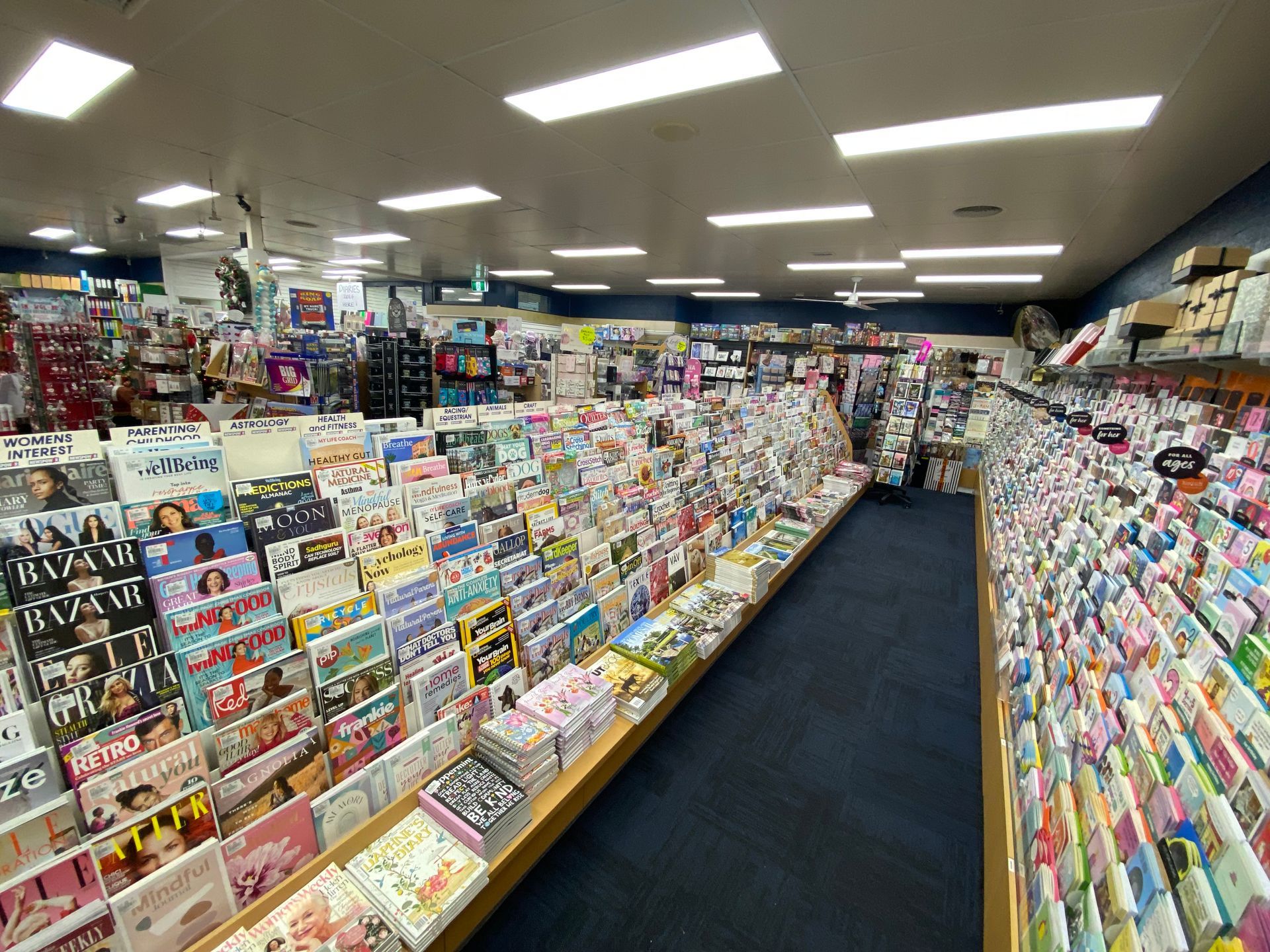Woman Checking Pile of Magazine — Local Newsagent in Moss Vale, NSW