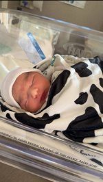 Sleeping newborn wrapped in black-and-white blanket in a hospital bassinet
