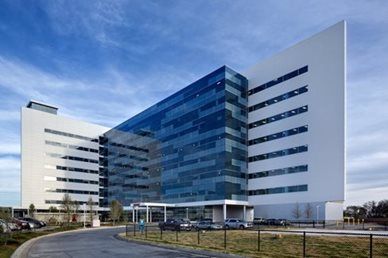 Modern office building with a blue glass center and white wings under a cloudy sky