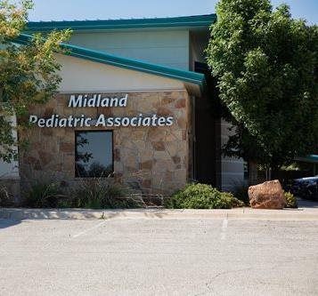 Midland Pediatric Associates building with stone facade, teal roof trim, and trees in front