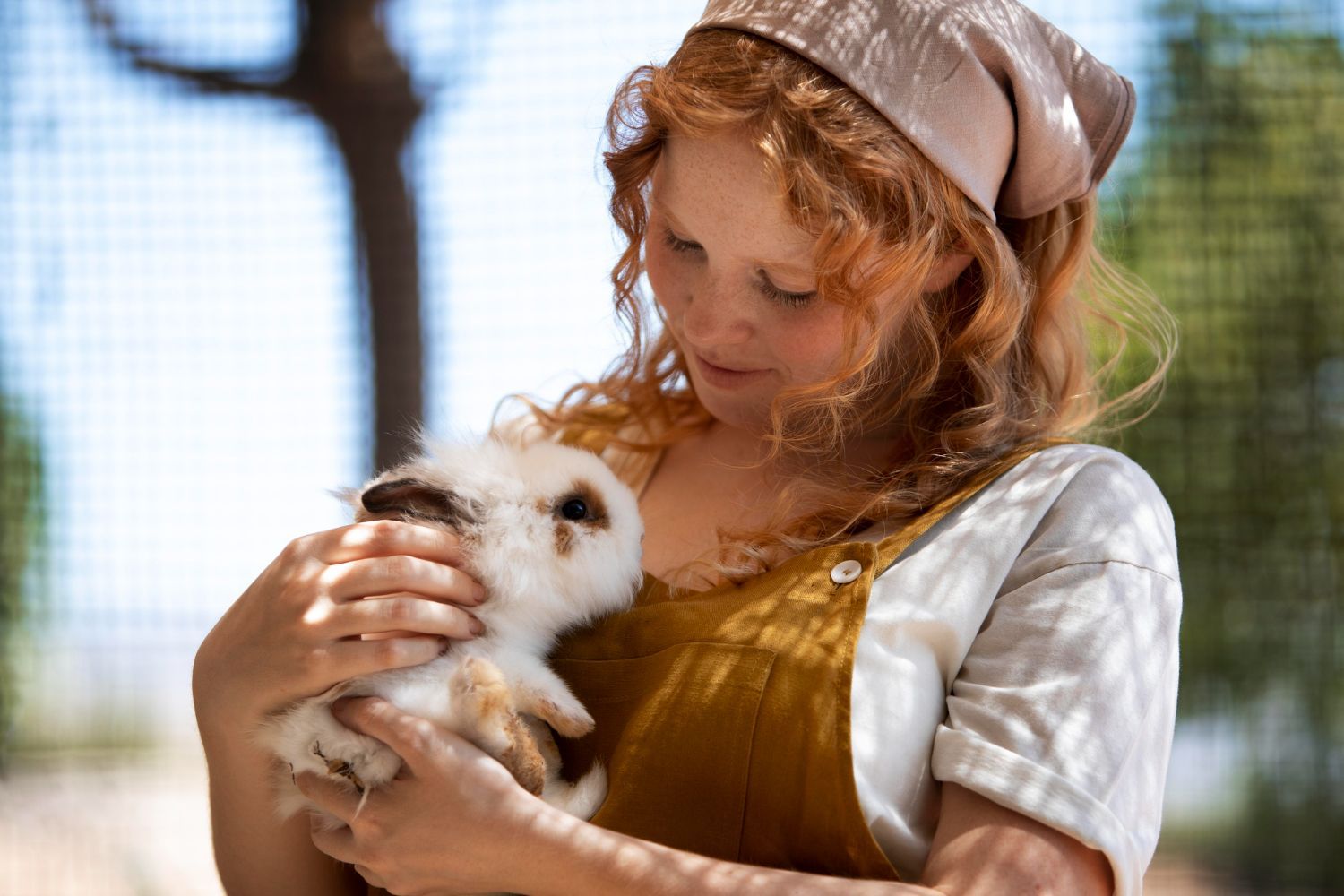Woman holding a white rabbit outdoors in soft sunlight