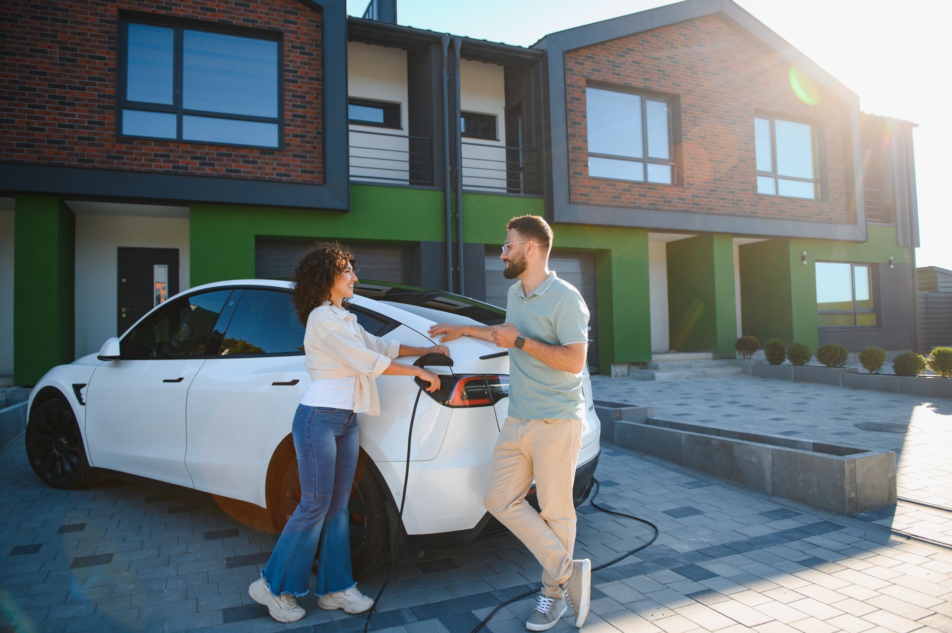 Two people exchanging car keys beside a white car in front of modern houses
