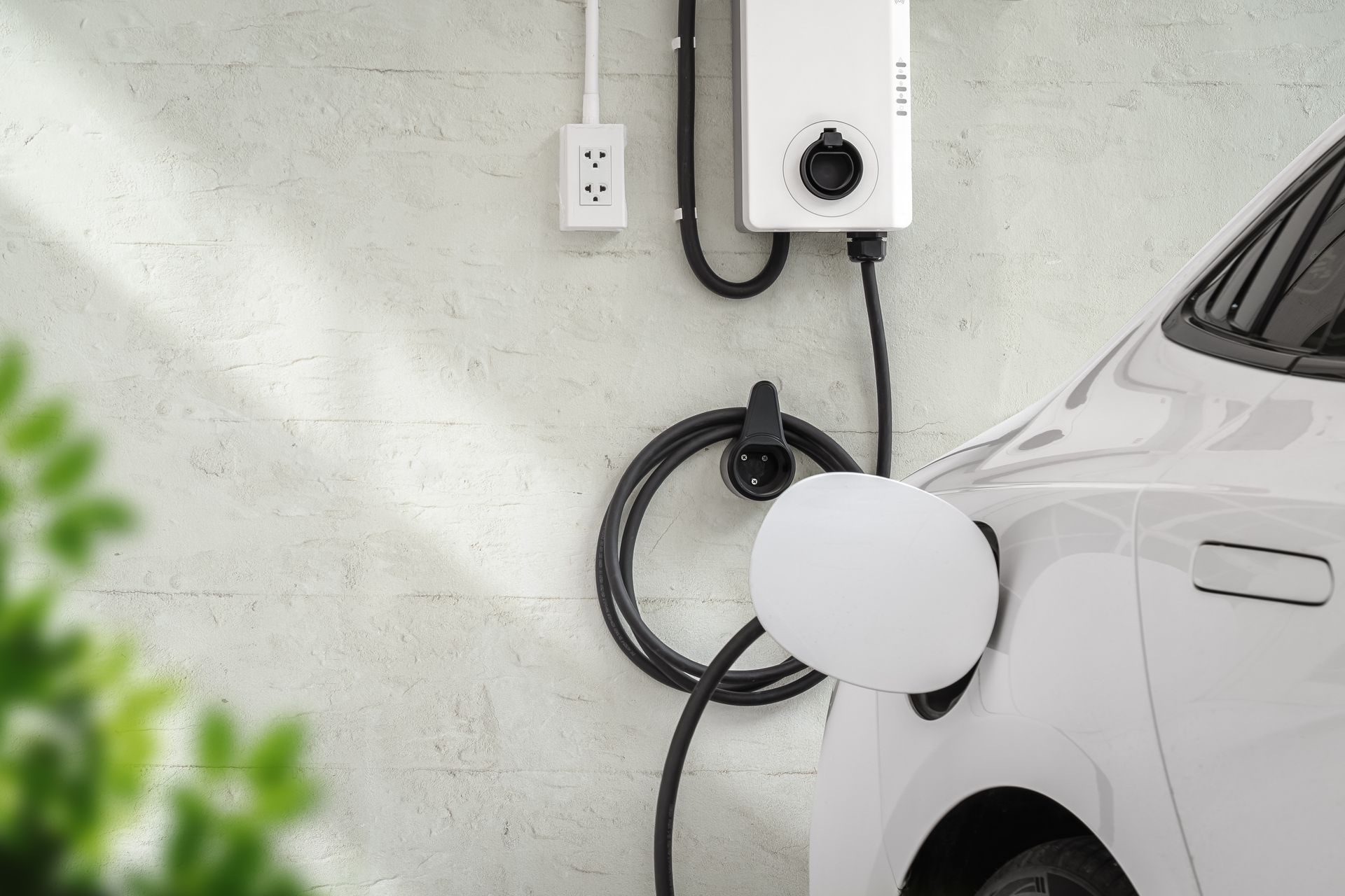 Electric car charging next to a wall-mounted charger in a garage