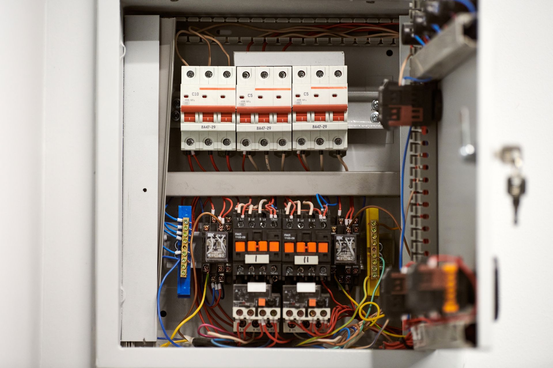 Open electrical panel with breakers, relays, and colored wiring inside a metal cabinet