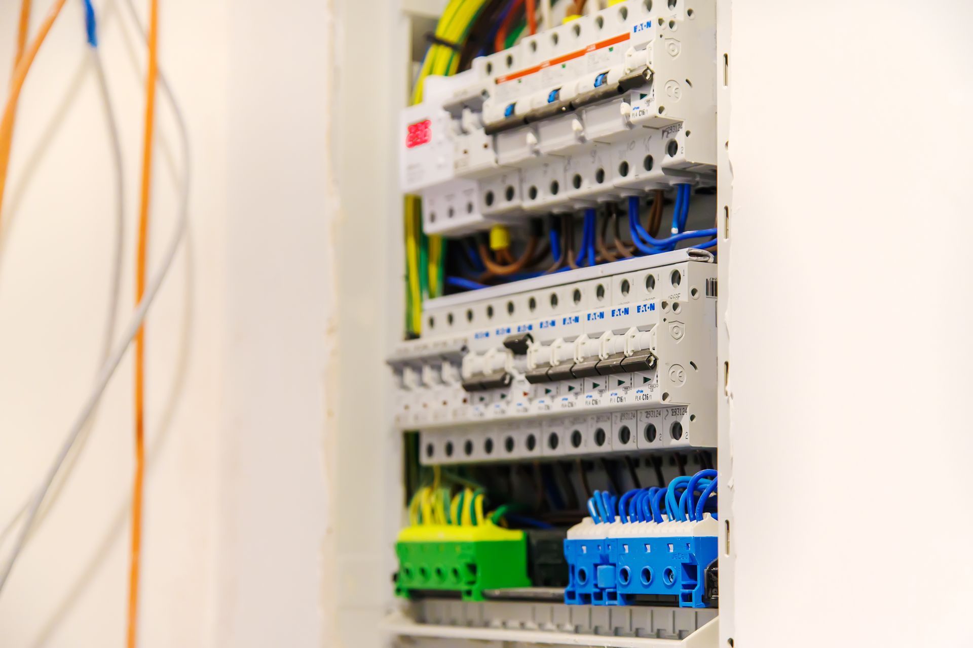 Electrical breaker panel with rows of circuit breakers and color-coded wiring inside a wall-mounted cabinet