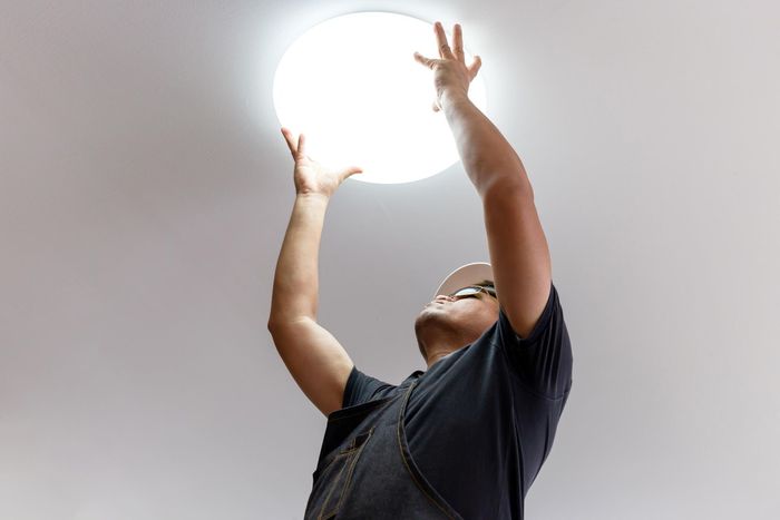 Person reaching up to install or adjust a round ceiling light.