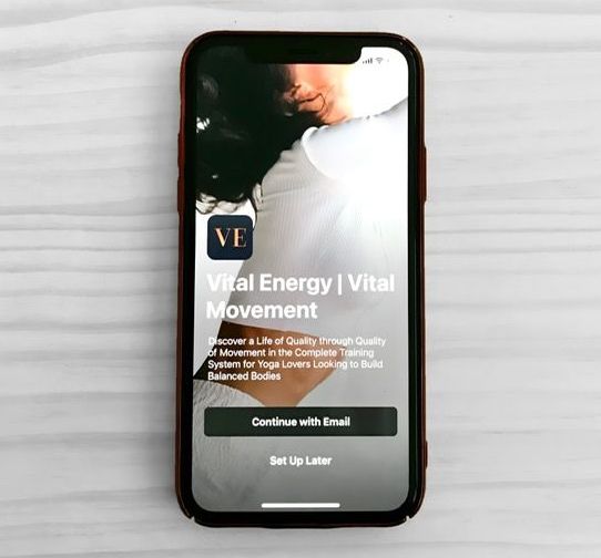 Smartphone screen displaying Vital Energy | Vital Movement app; person in white shirt, email sign-up.