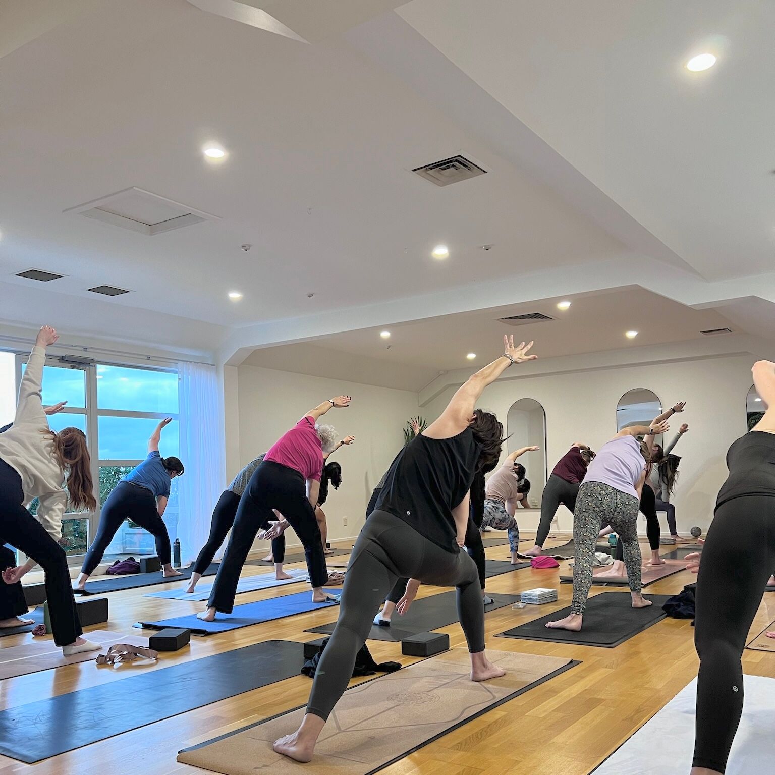 A group of people are doing yoga in a large room.