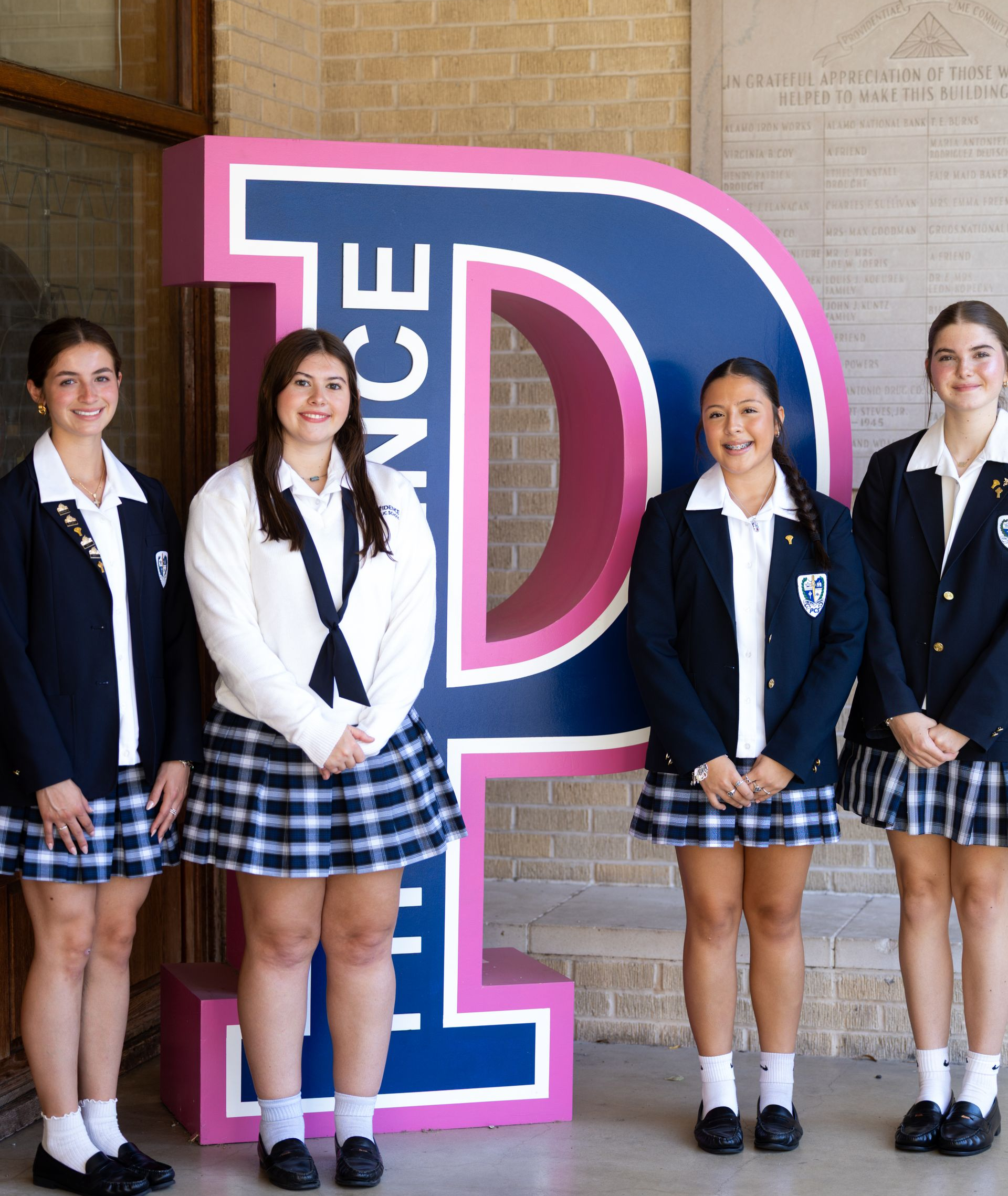 A group of girls in school uniforms are posing for a picture.