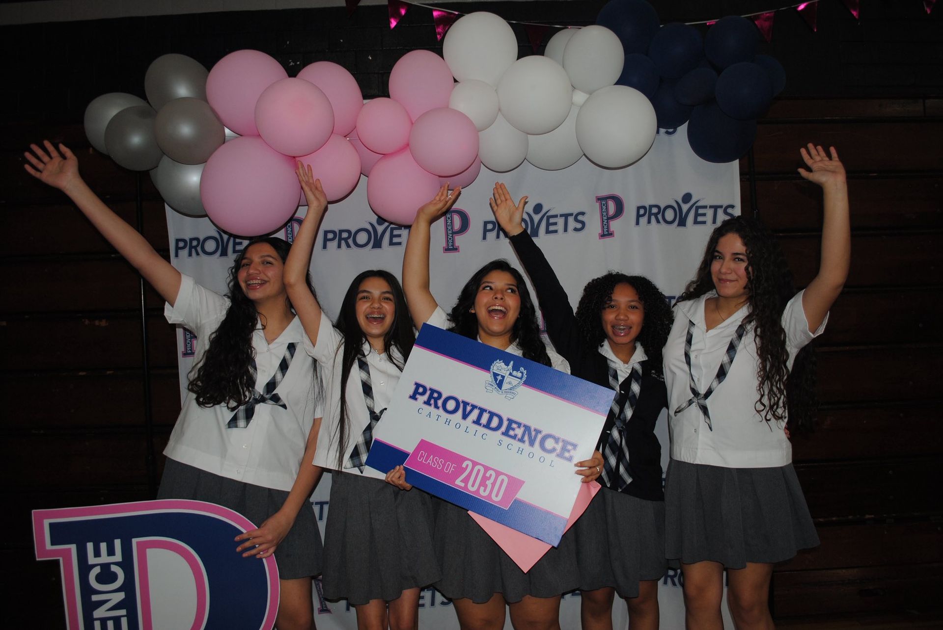 A group of girls are standing in front of a sign that says sisterhood begins here pcs