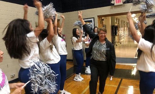 A group of cheerleaders are cheering on a woman in a gym.