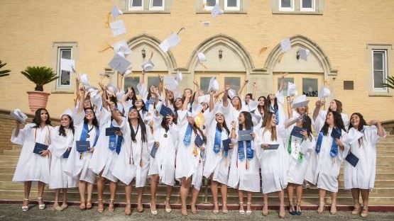 A group of graduates are throwing their caps in the air in front of a building.