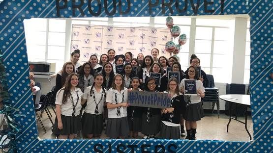 A group of girls are posing for a picture in front of a blue frame.