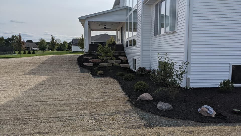 White house with stone landscaping and gravel driveway.