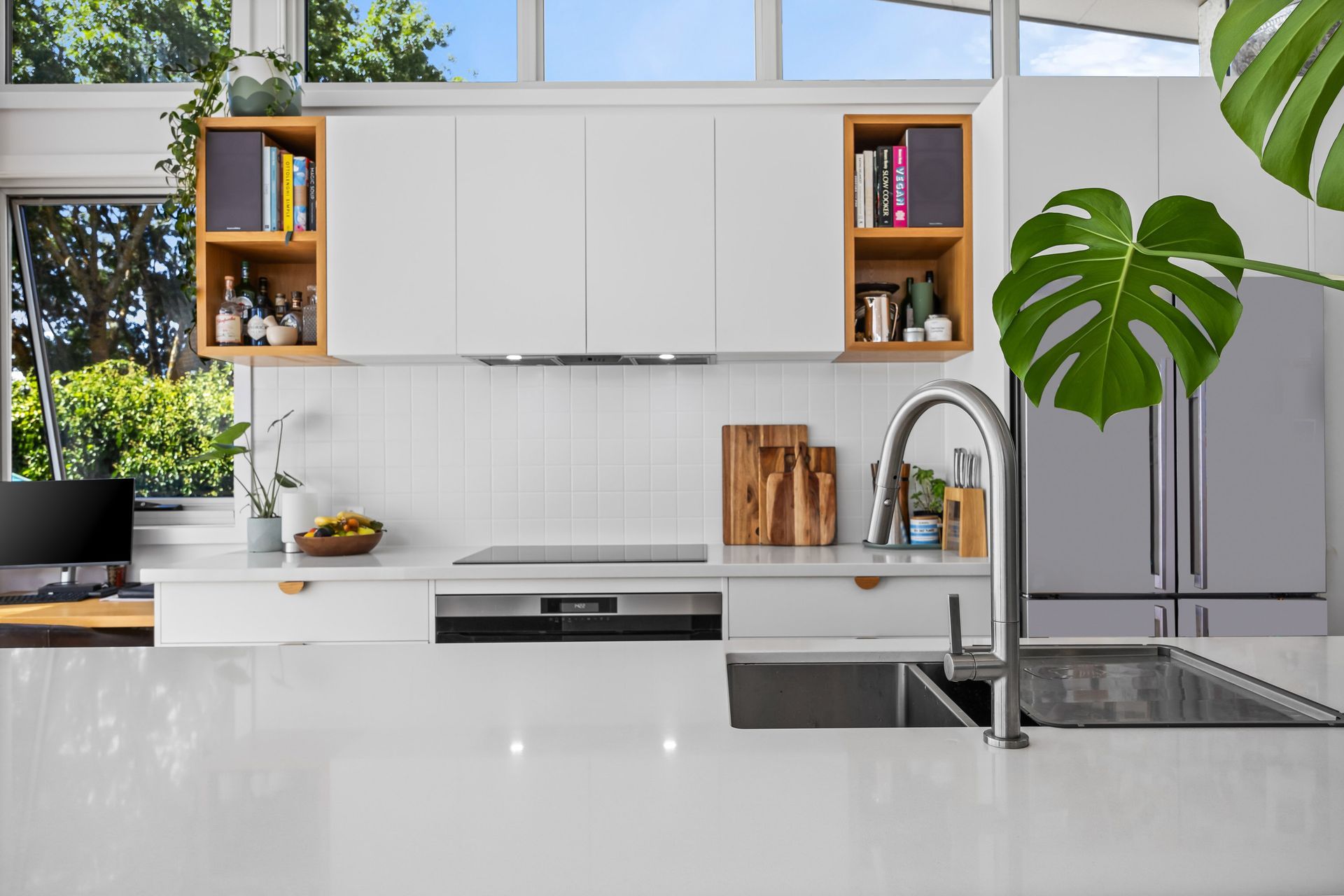 Modern kitchen with minimalist cabinetry, integrated rangehood and timber shelf accents.
