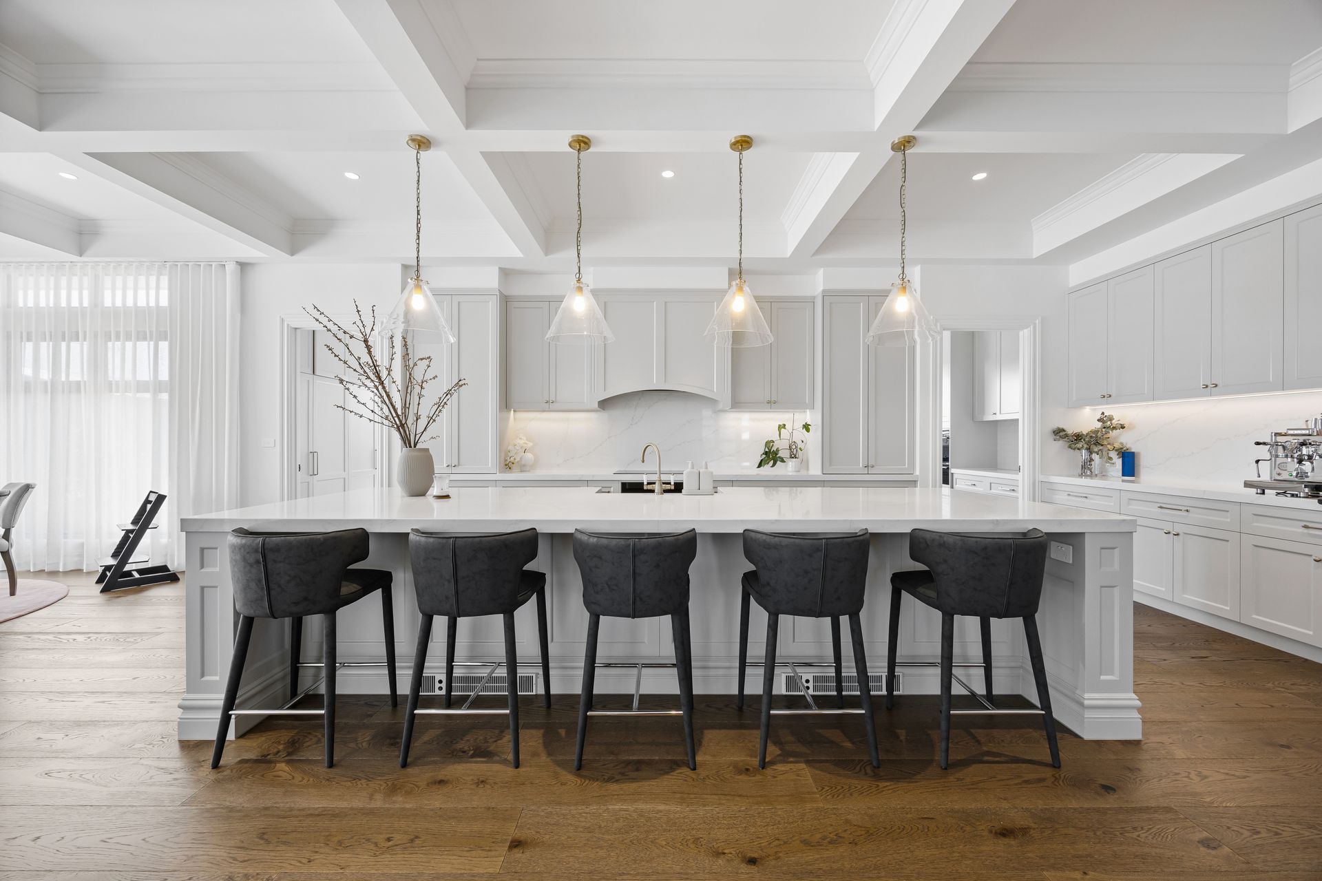 White kitchen with feature lighting and bar seating