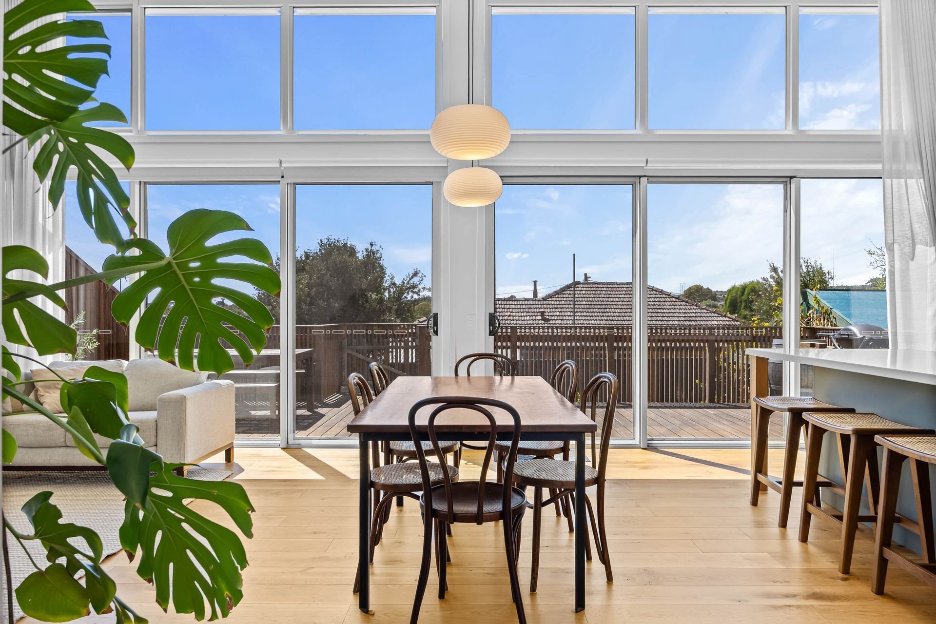 Light-filled dining space opening to outdoor deck through full-height glass doors.
