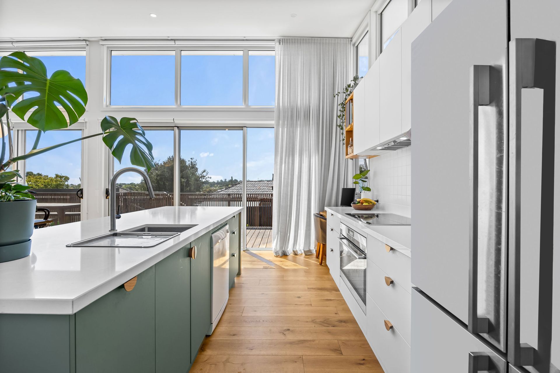  Sleek kitchen with green island, double sink and leafy views.