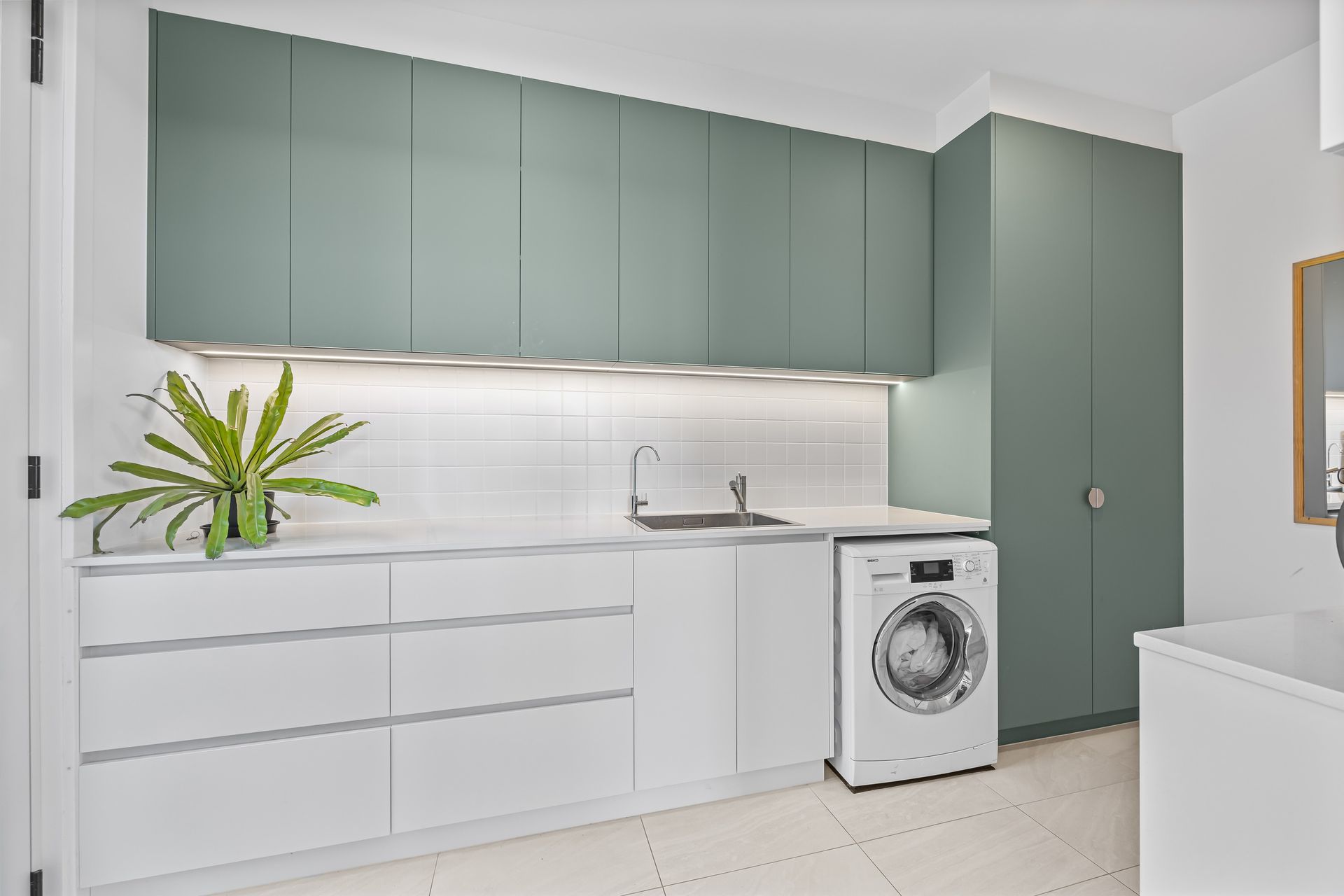 Clean-lined compact kitchen area connecting to laundry zone.