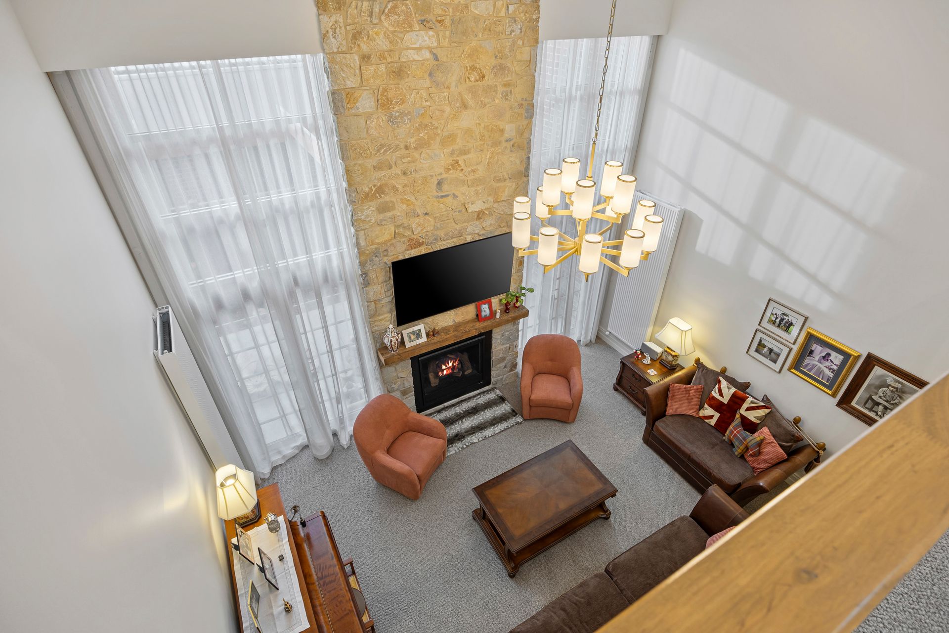 Double-height living space with chandelier and textured stone wall