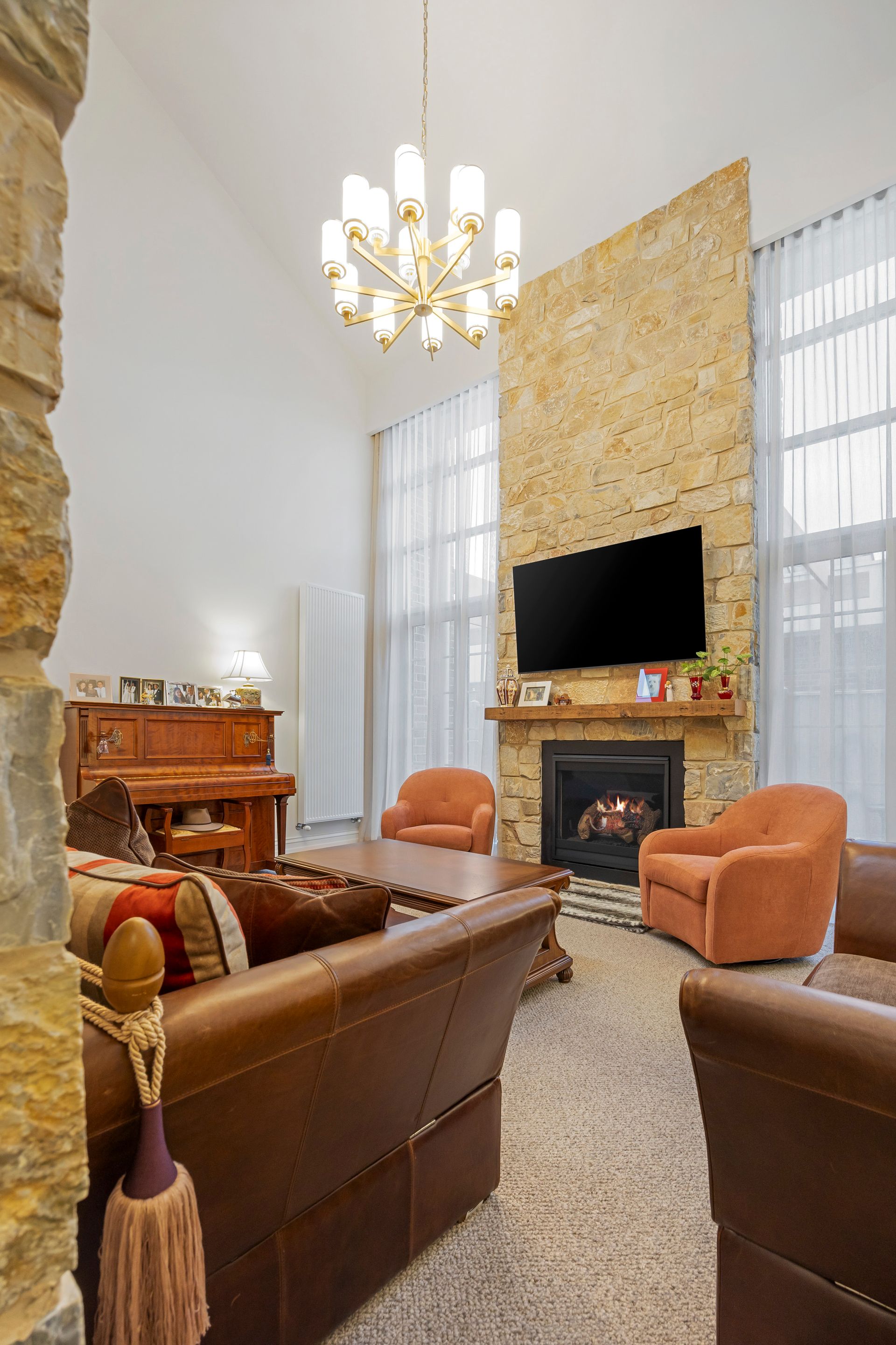 Double-height living space with chandelier and textured stone wall