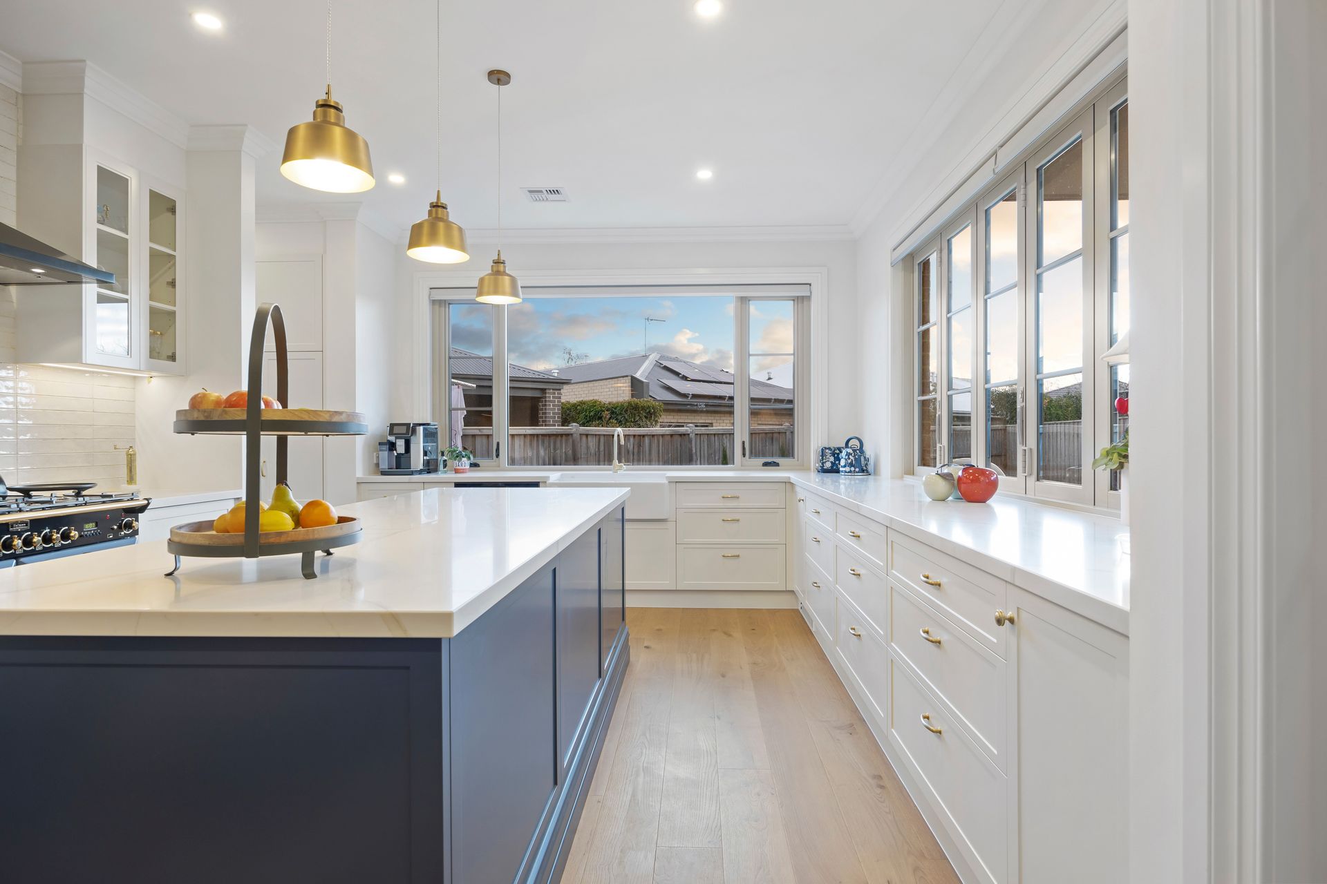 Spacious open-plan kitchen with navy island and pendant lights