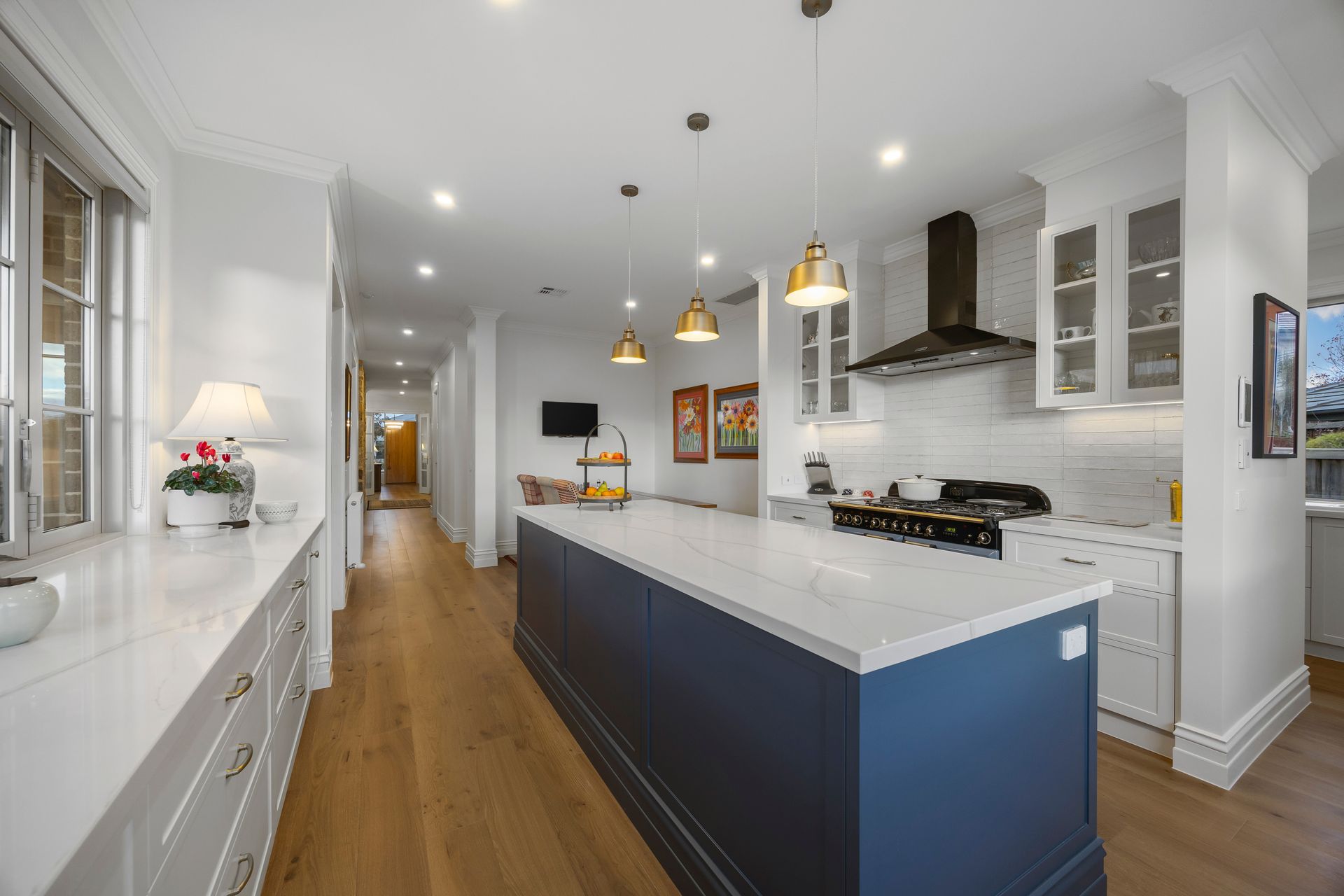 Spacious open-plan kitchen with navy island and pendant lights