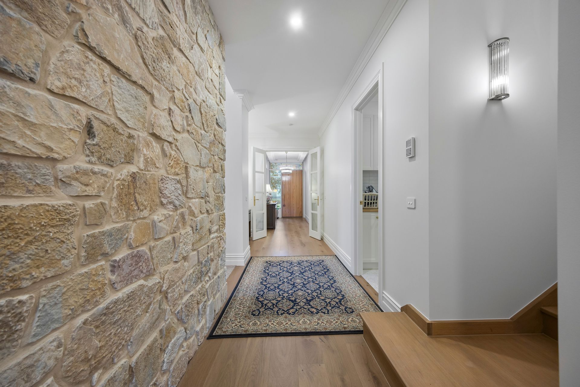 Natural stone hallway with recessed lighting and timber floors