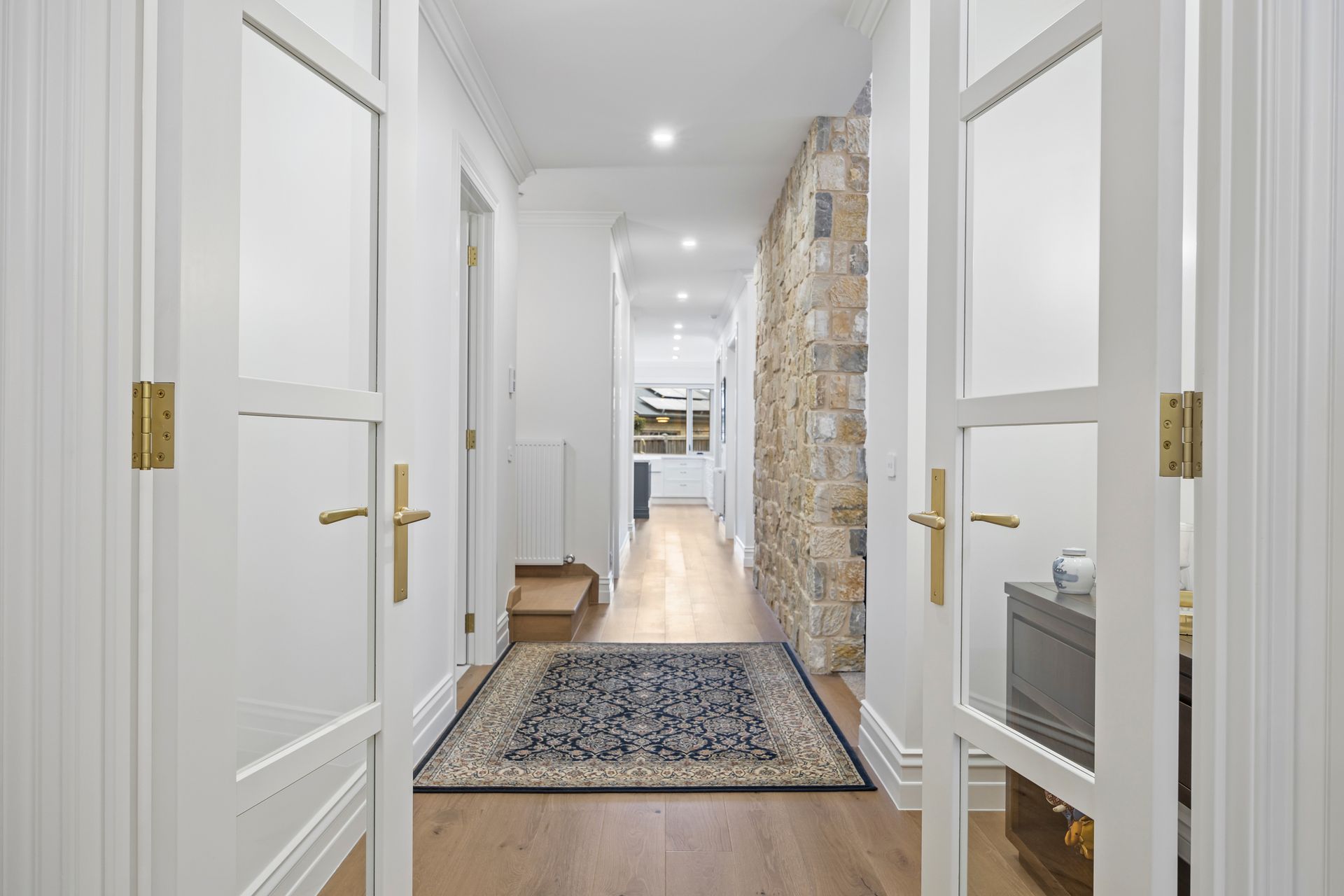 Elegant hallway with timber flooring and stone feature wall